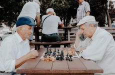 2 personas mayores jugando ajedrez en una mesa de madera